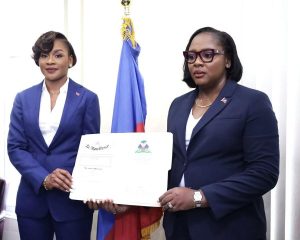 À à gauche la nouvelle Directrice Générale Lovely François, à droite la ministre Sandra Paulemon tenant ensemble l'empliation